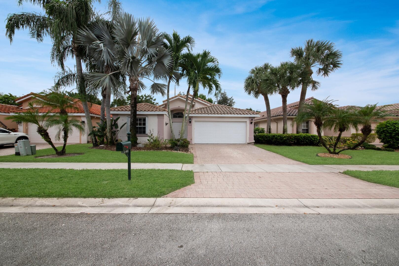 a palm tree sitting in front of a house with a big yard