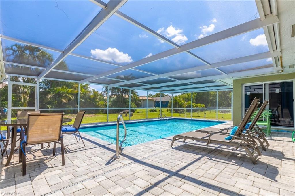 a view of swimming pool with lounge chair and dinning table under an umbrella