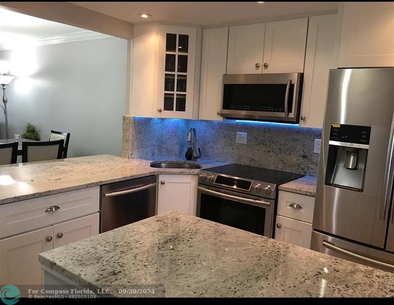 a kitchen with stainless steel appliances granite countertop a stove microwave and sink