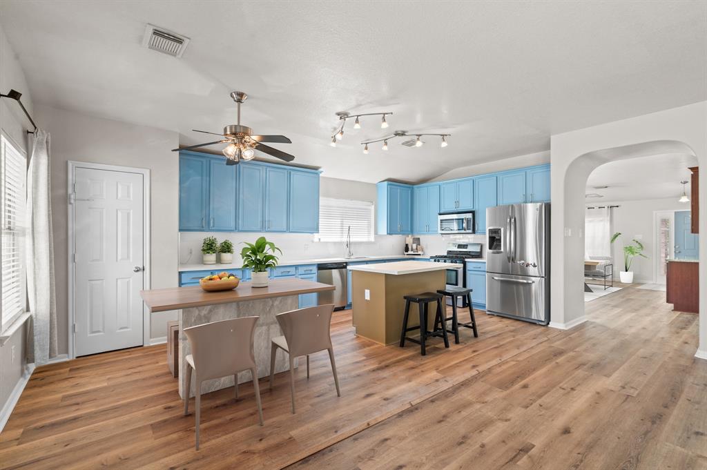 a kitchen with a dining table chairs refrigerator and cabinets