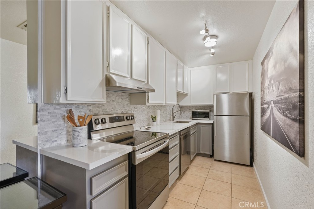 a kitchen with stainless steel appliances granite countertop a sink a stove a refrigerator and island