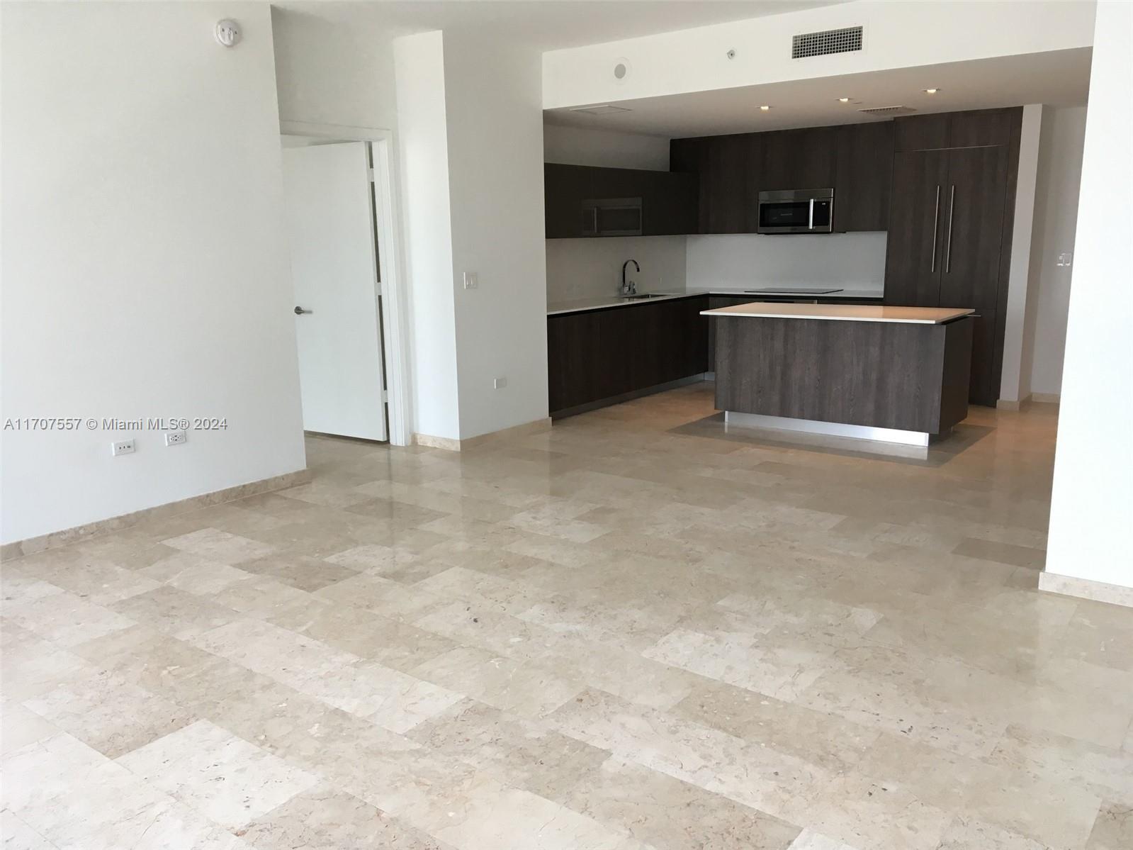 a view of kitchen with stainless steel appliances cabinets and empty room