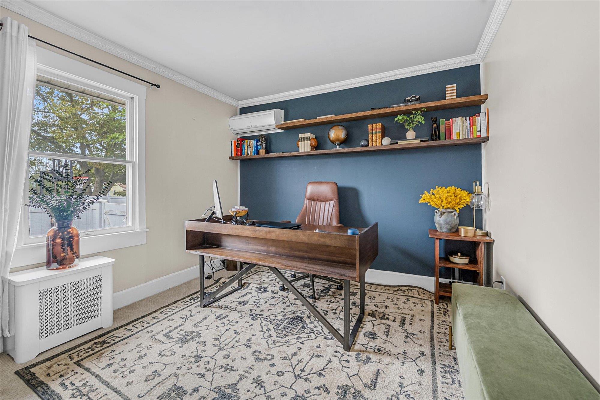 Carpeted office featuring a wall unit AC, radiator heating unit, and ornamental molding