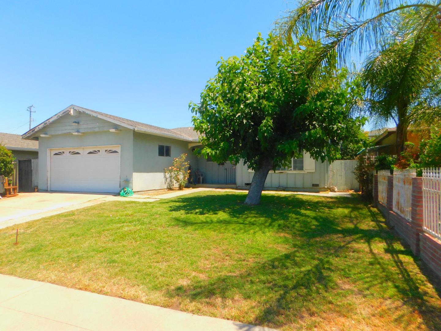 a view of a house with a backyard and a tree