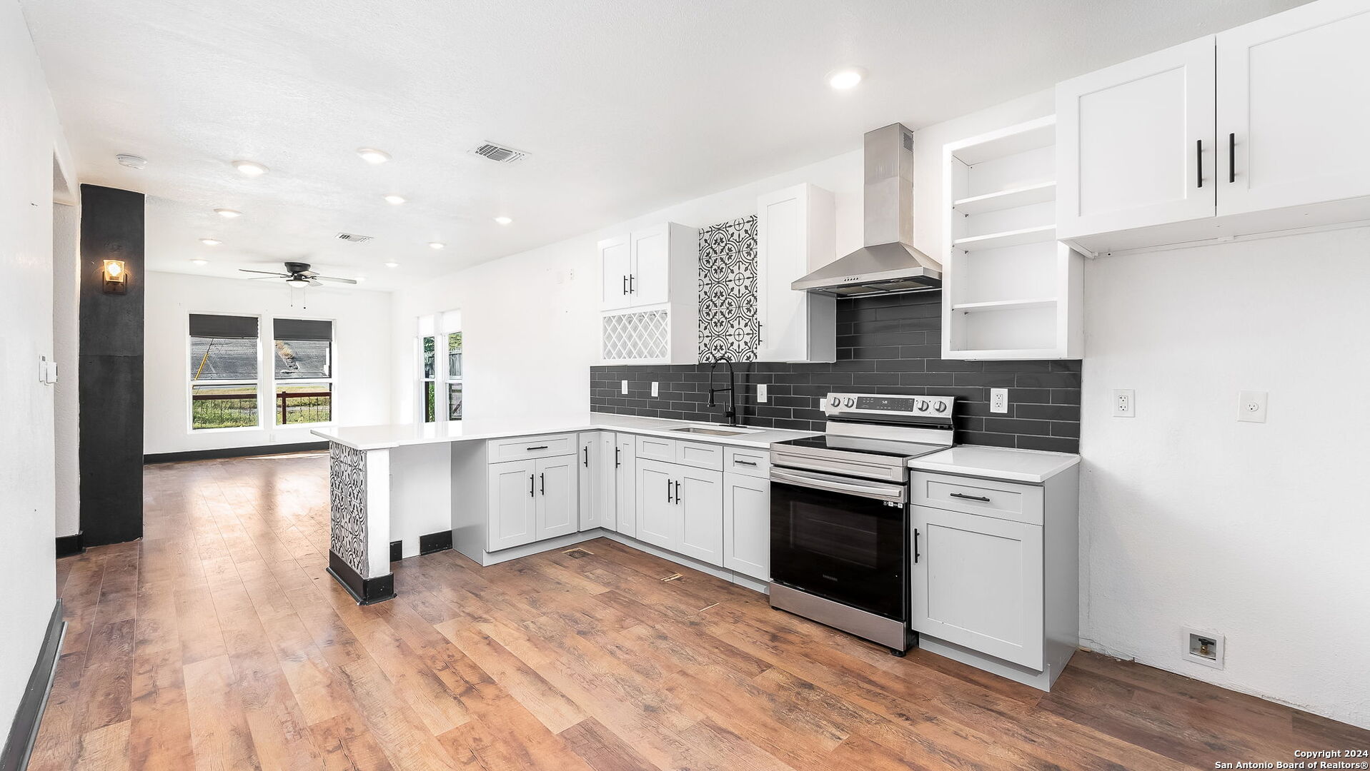 a kitchen with granite countertop a stove top oven a sink dishwasher and white cabinets with wooden floor