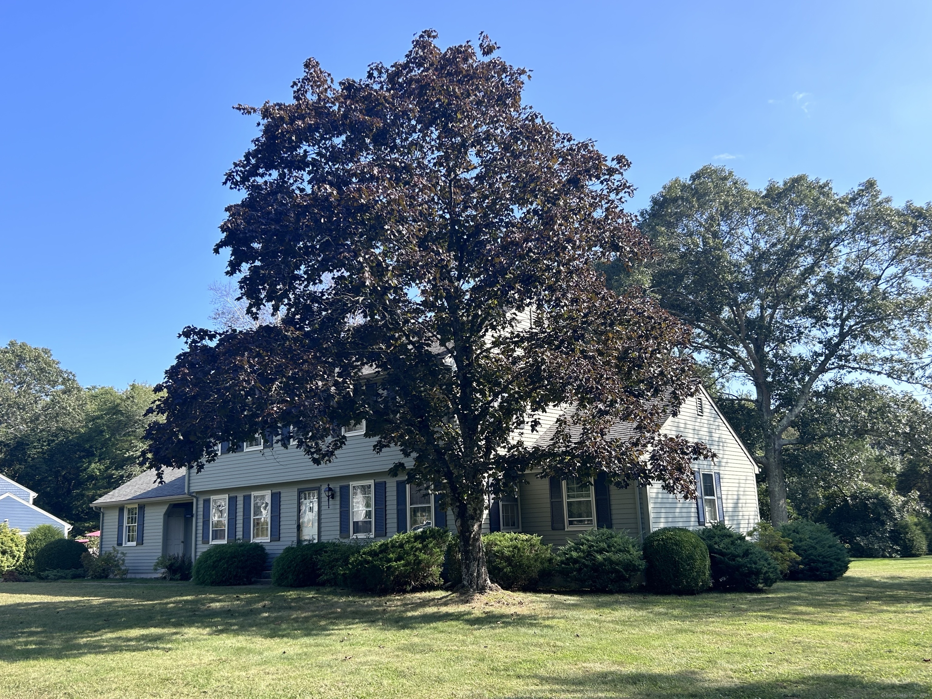 a front view of a house with a garden and trees