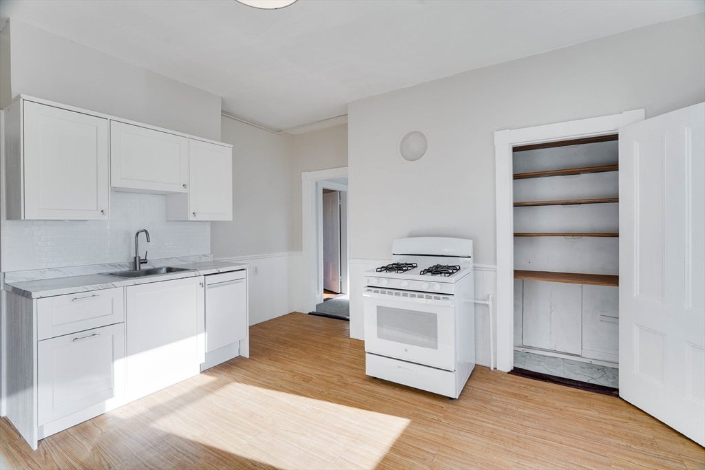 a kitchen with a stove cabinets and wooden floor