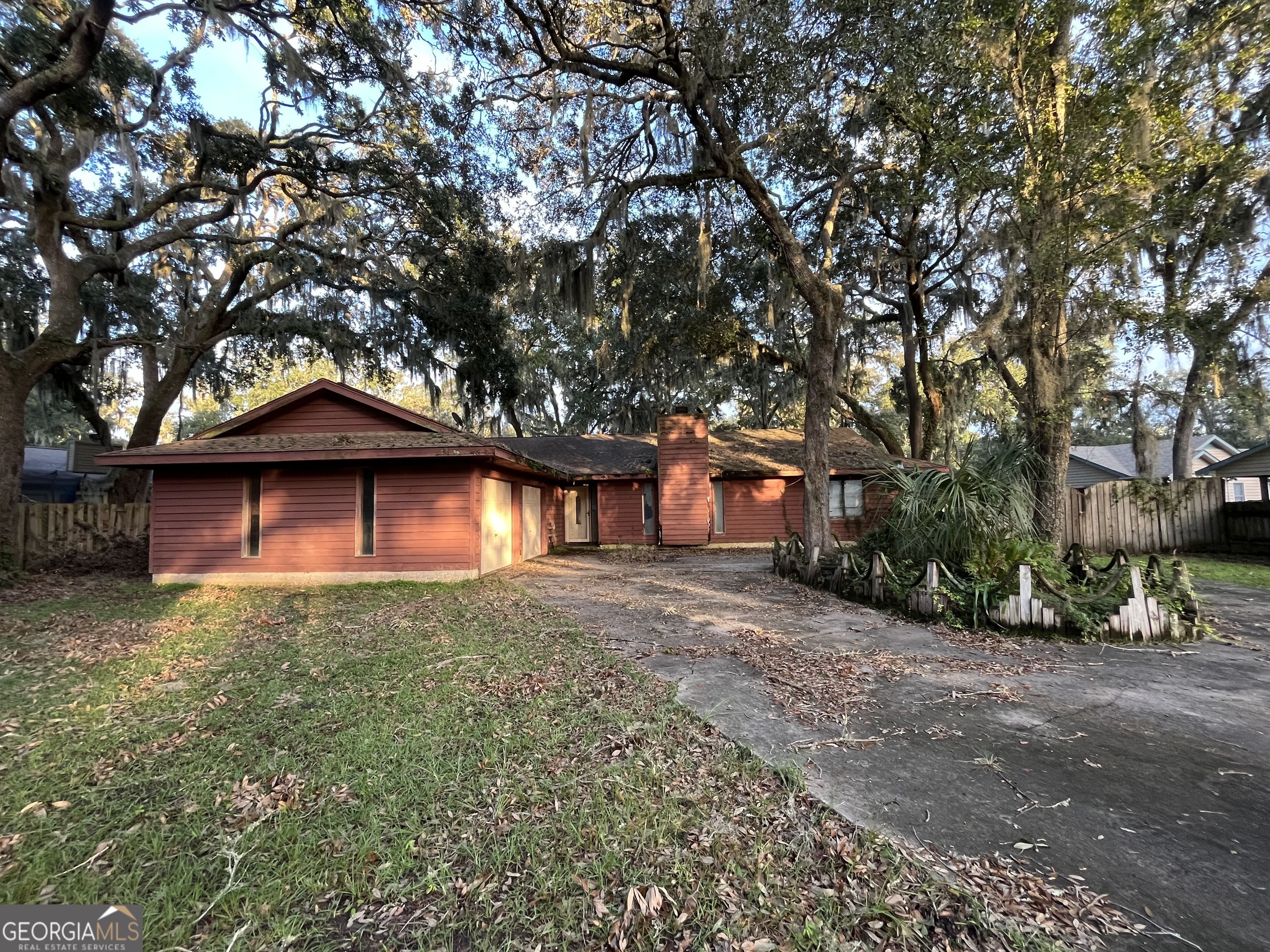 a small barn in front of a house with a large tree