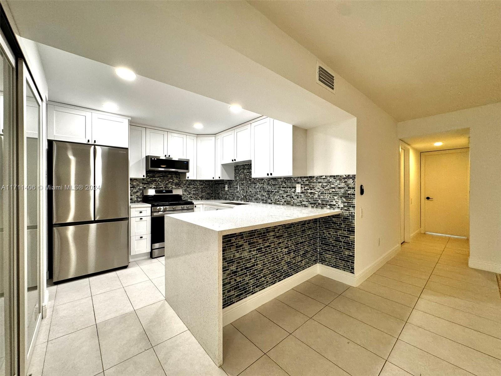 a kitchen with stainless steel appliances a refrigerator sink and microwave