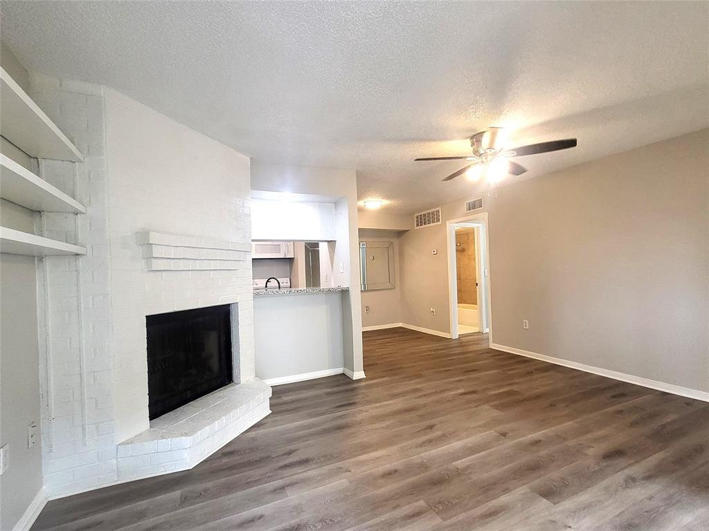 a view of a livingroom with a fireplace a ceiling fan and wooden floor