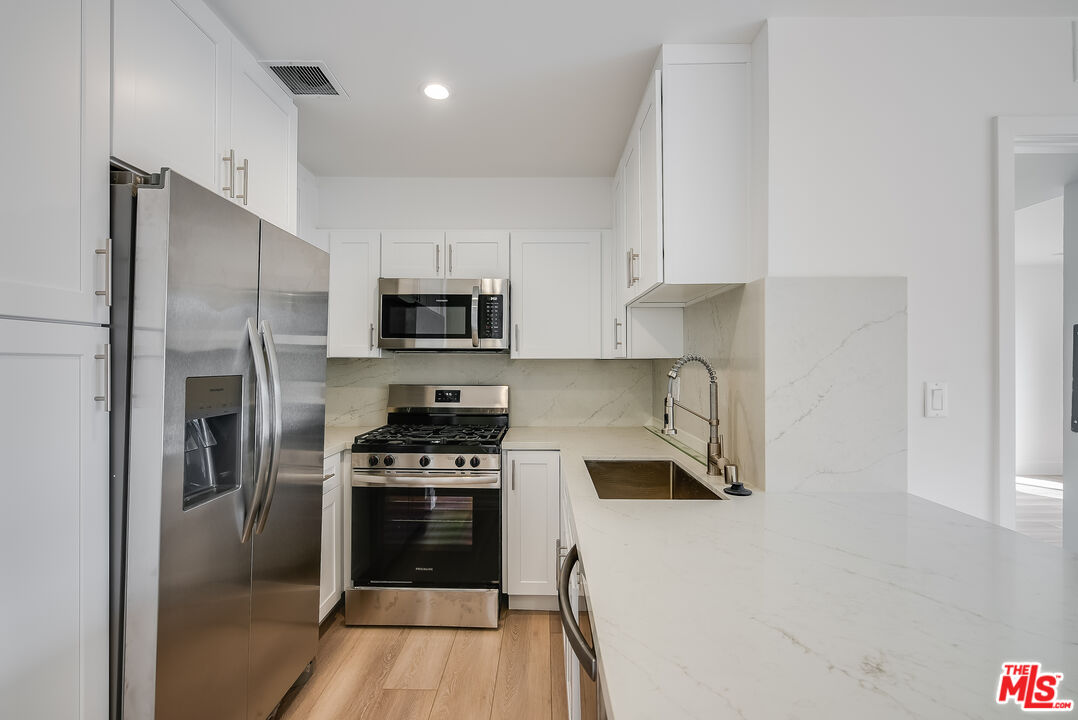 a kitchen with cabinets stainless steel appliances and a counter space