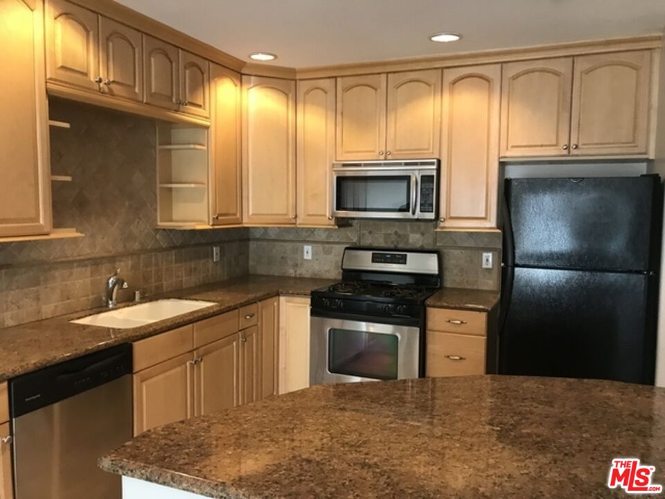 a kitchen with stainless steel appliances granite countertop a refrigerator stove and sink