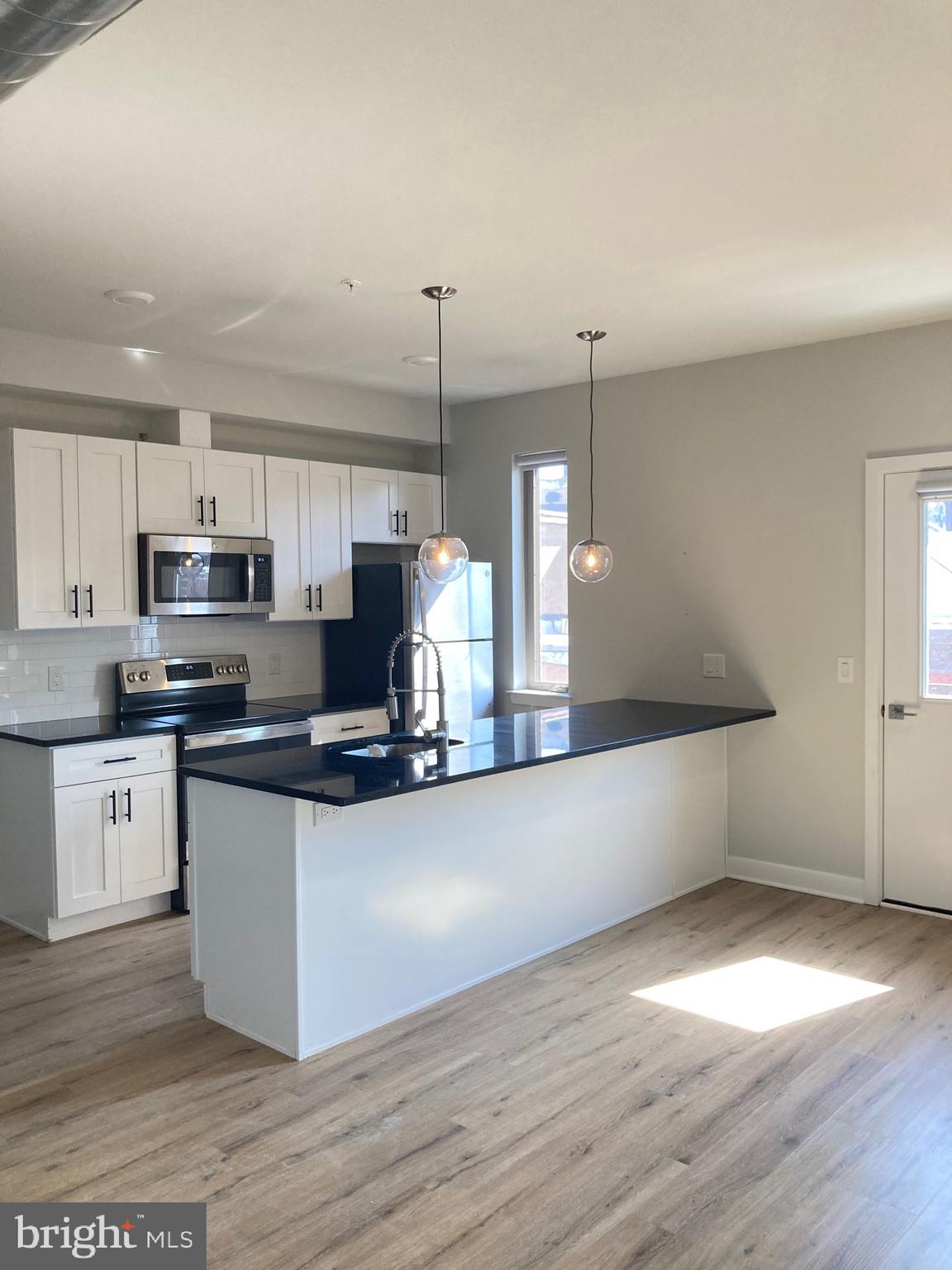 a kitchen with stainless steel appliances granite countertop a sink a stove and a wooden floors