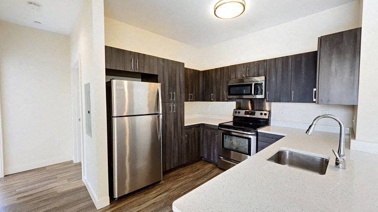 a kitchen with granite countertop a refrigerator and a stove top oven