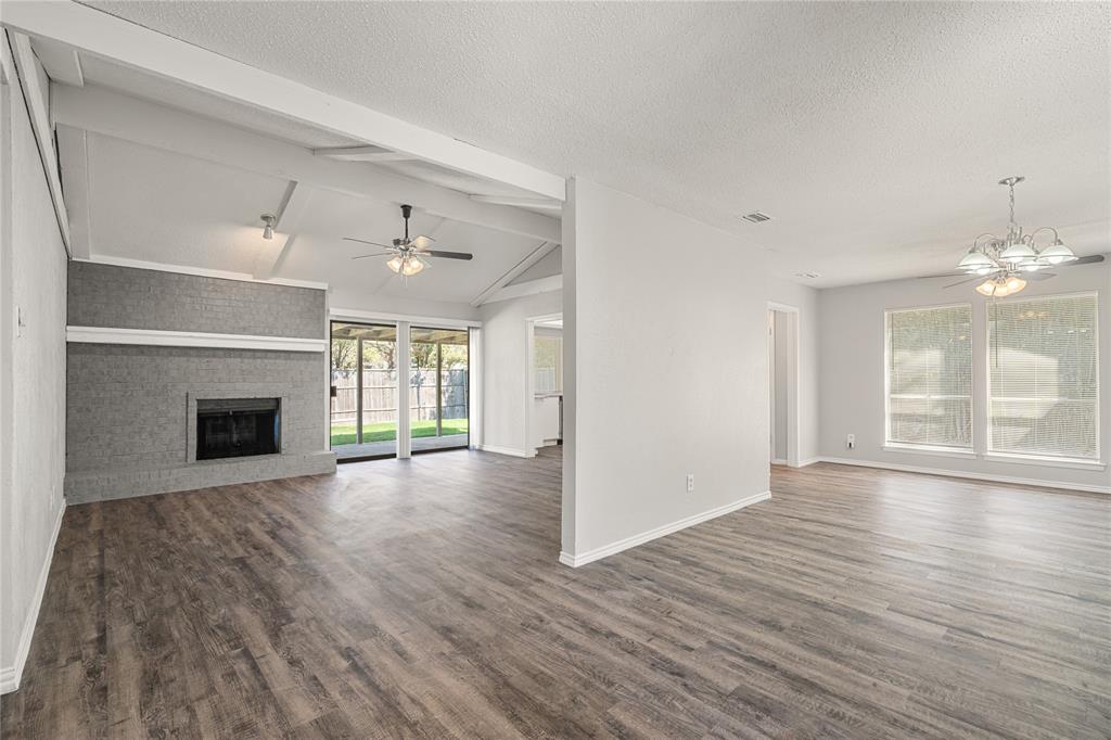 a view of an empty room with wooden floor fireplace and a window