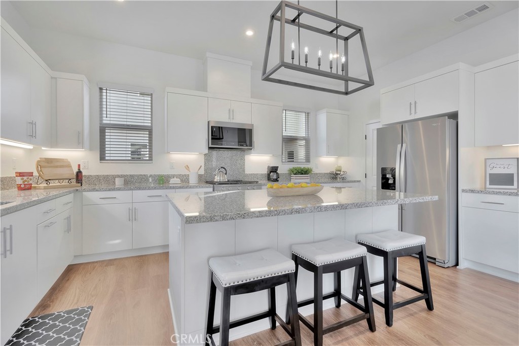 a kitchen with stainless steel appliances granite countertop a dining table chairs refrigerator and cabinets