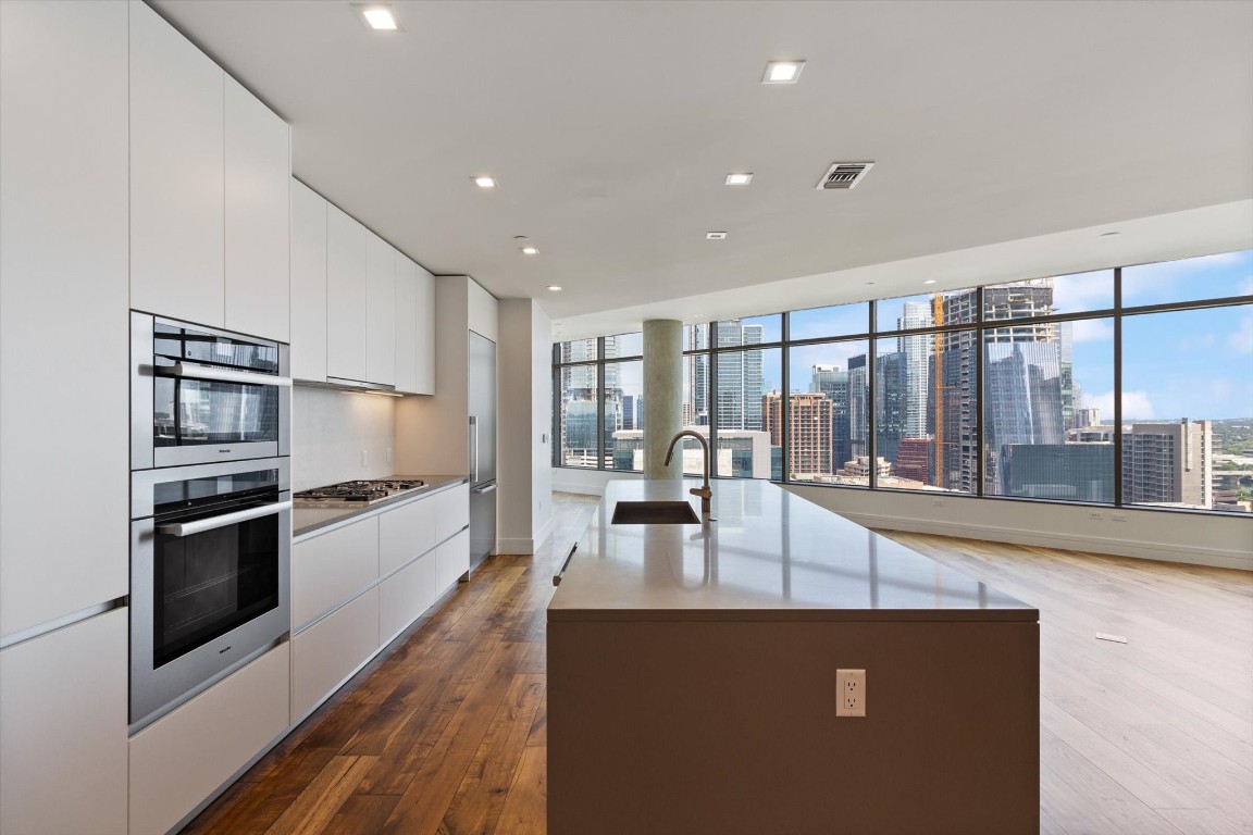 a view of a kitchen with kitchen island a large counter top space a sink appliances and cabinets