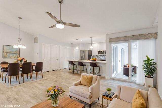 a living room with furniture kitchen view and a chandelier