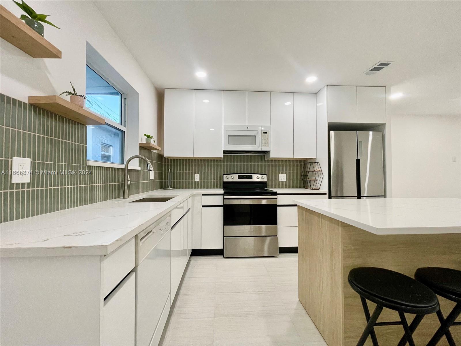 a kitchen with a sink a stove a refrigerator and chairs