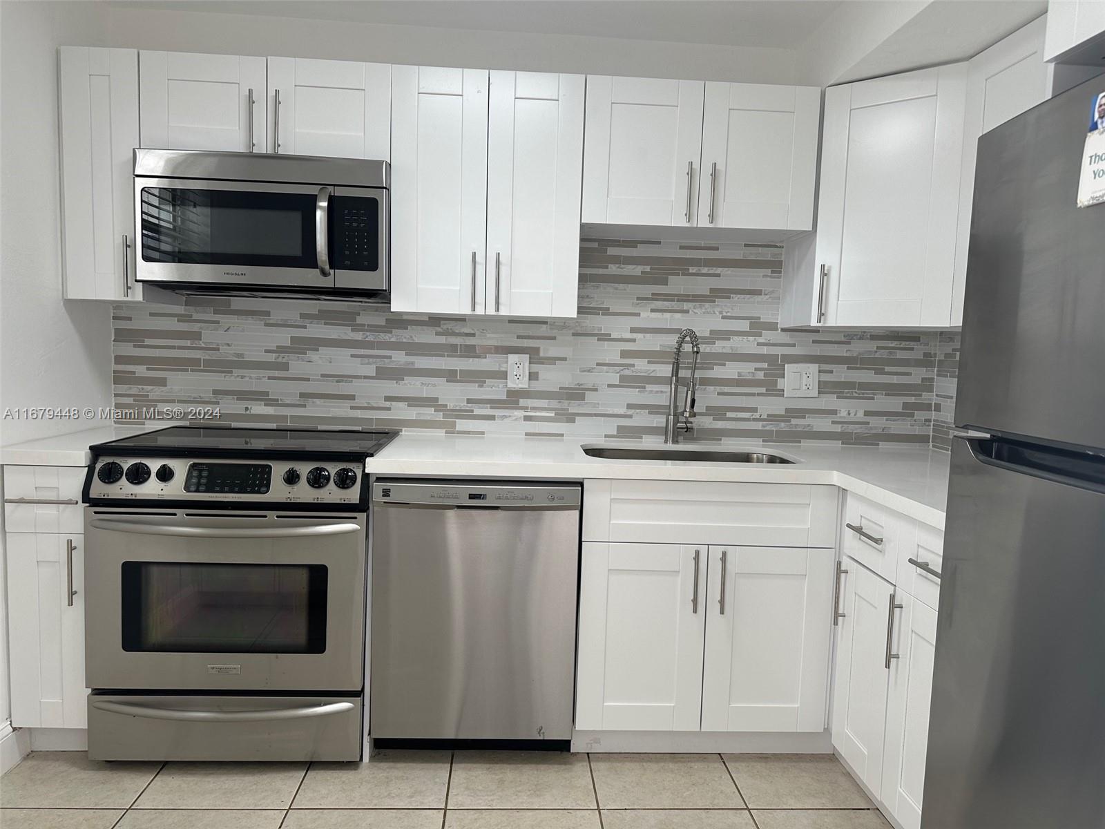 a kitchen with stainless steel appliances granite countertop white cabinets a microwave a sink and a counter space