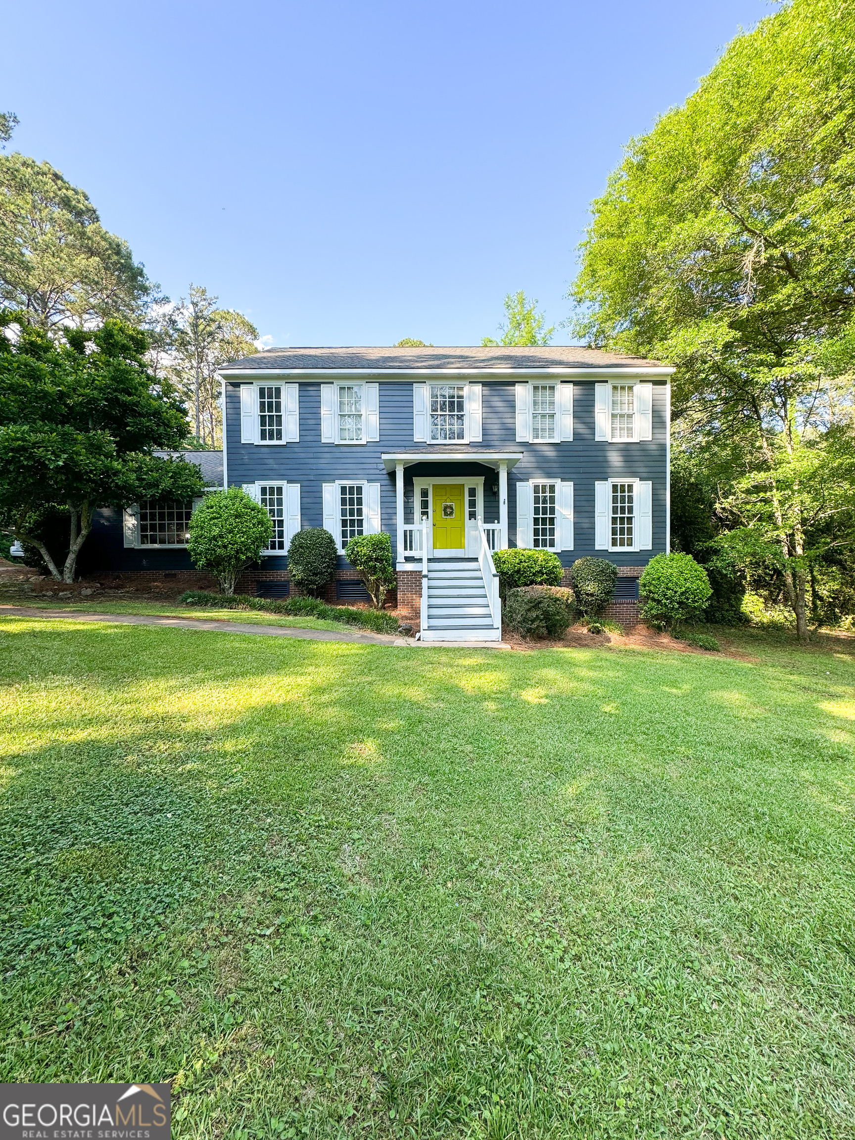 a front view of a house with garden and trees