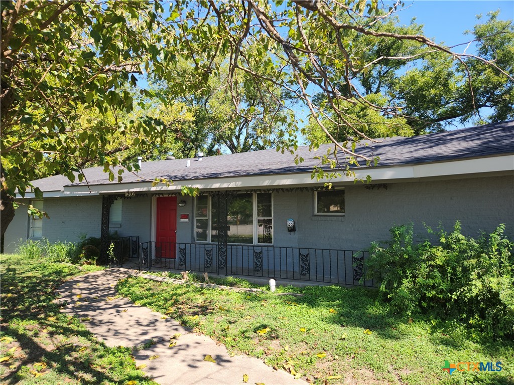 a backyard of a house with large trees and plants