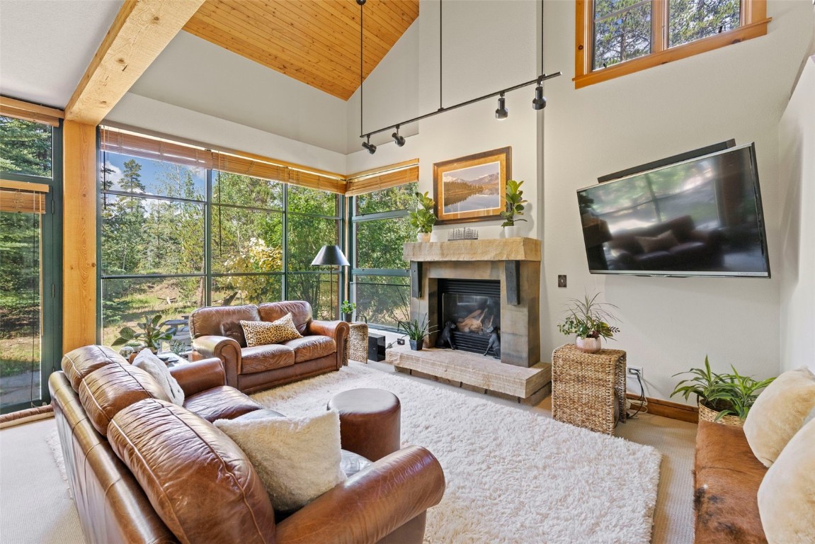 Living room with wooden ceiling, a tile fireplace, a healthy amount of sunlight, and high vaulted ceiling