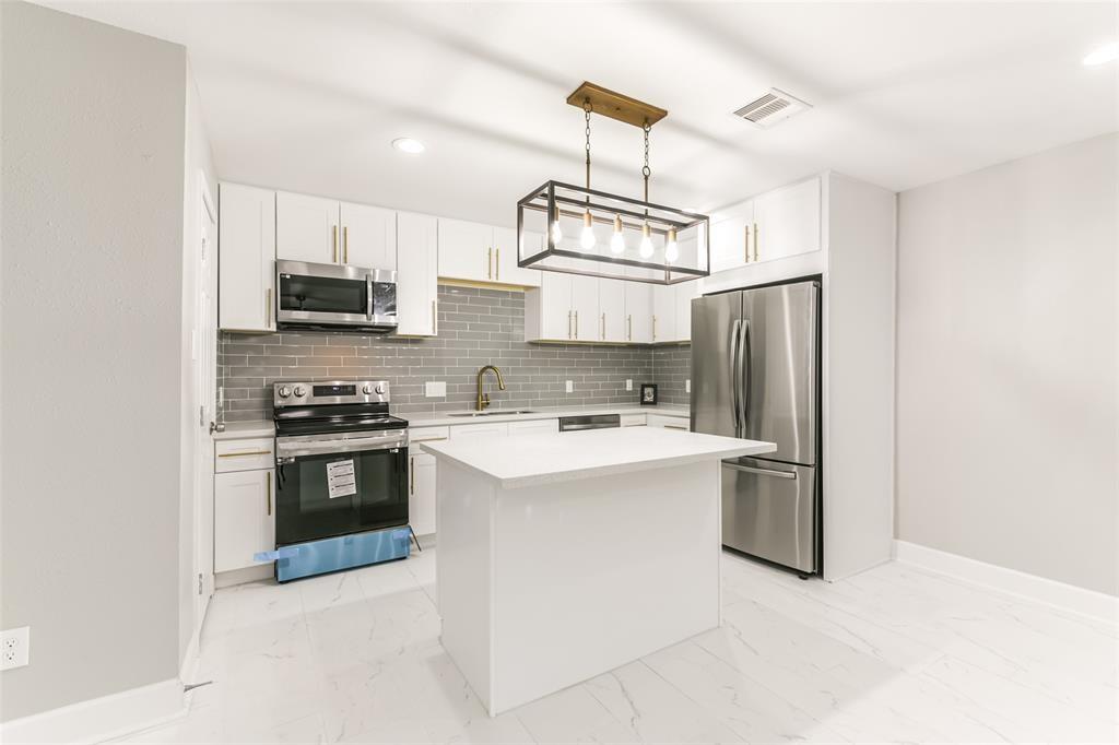 a kitchen with kitchen island white cabinets stainless steel appliances and a sink