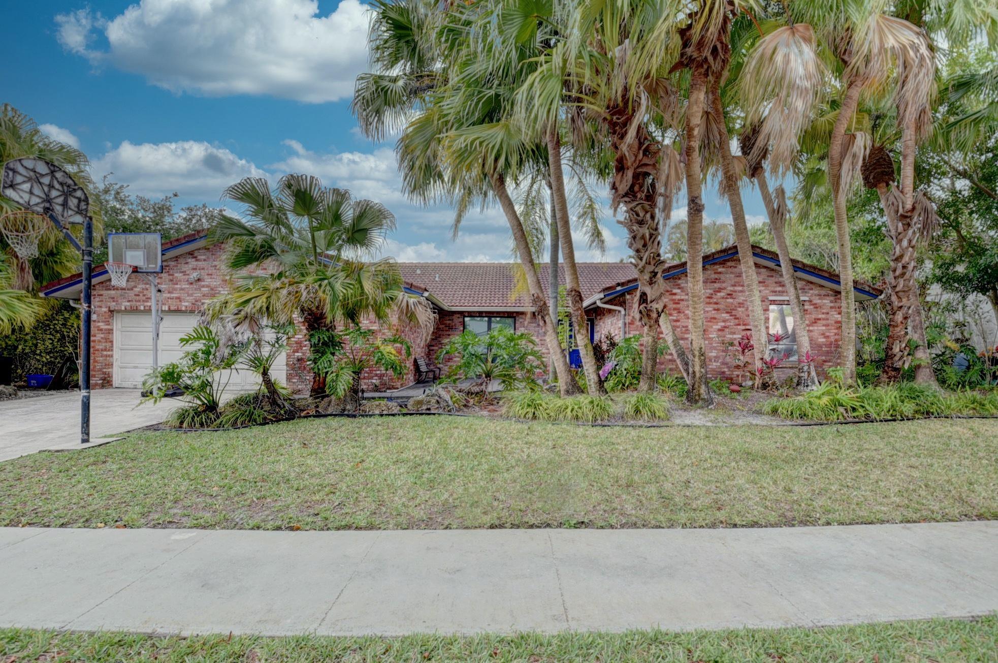 a view of a house with a yard and palm trees