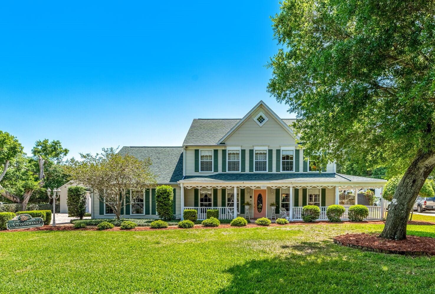 a front view of a house with a garden and trees