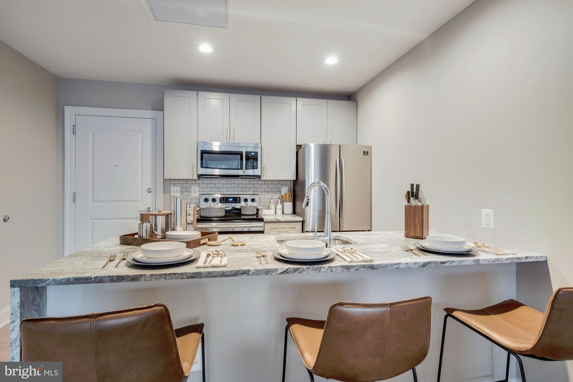 a kitchen with stainless steel appliances granite countertop a sink refrigerator and cabinets