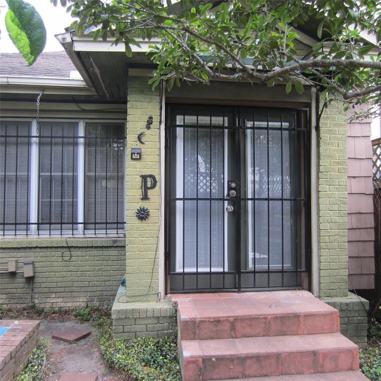 Charming entry with security bars, a decorative front door, and a small porch area with steps. Surrounded by greenery for added curb appeal.