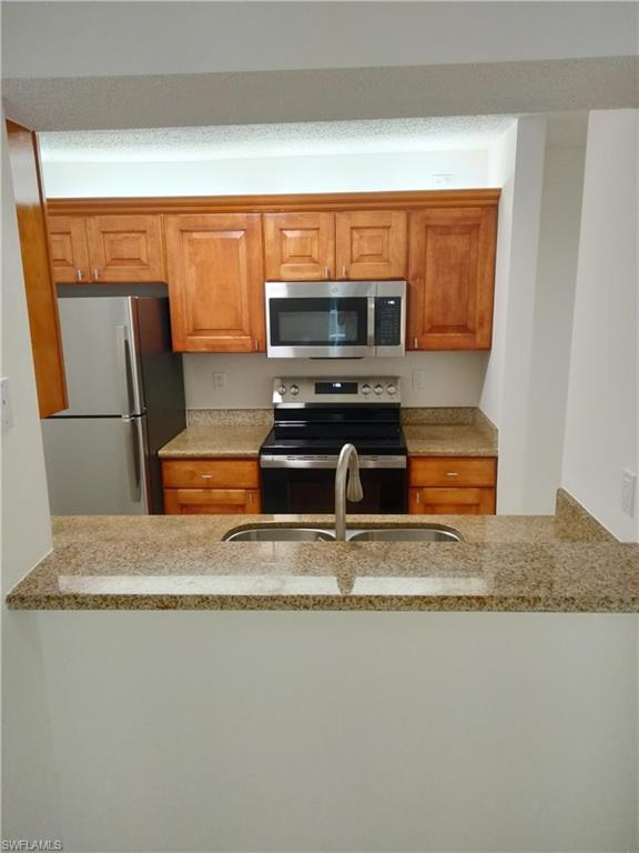 a kitchen with stainless steel appliances granite countertop a sink refrigerator and microwave