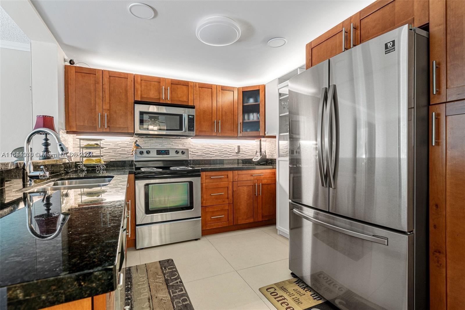 a kitchen with granite countertop a refrigerator stove and microwave