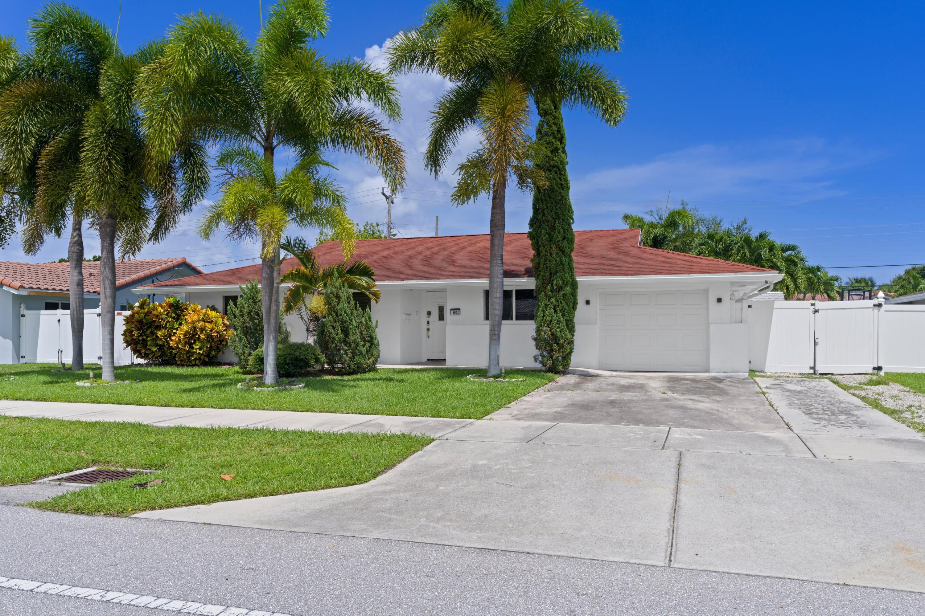 a view of a house with a yard and palm trees