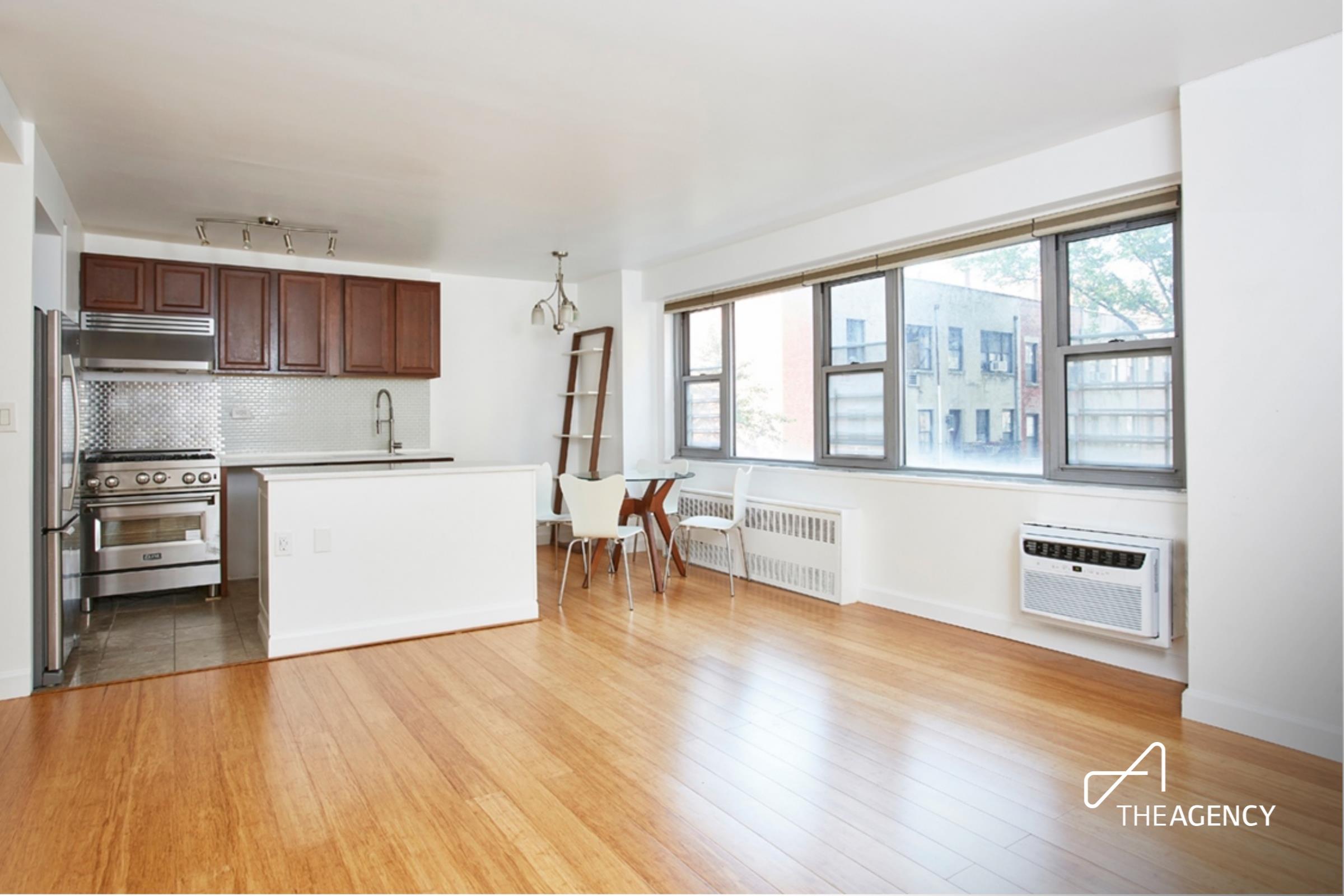 a living room with stainless steel appliances wooden floors and a view of kitchen