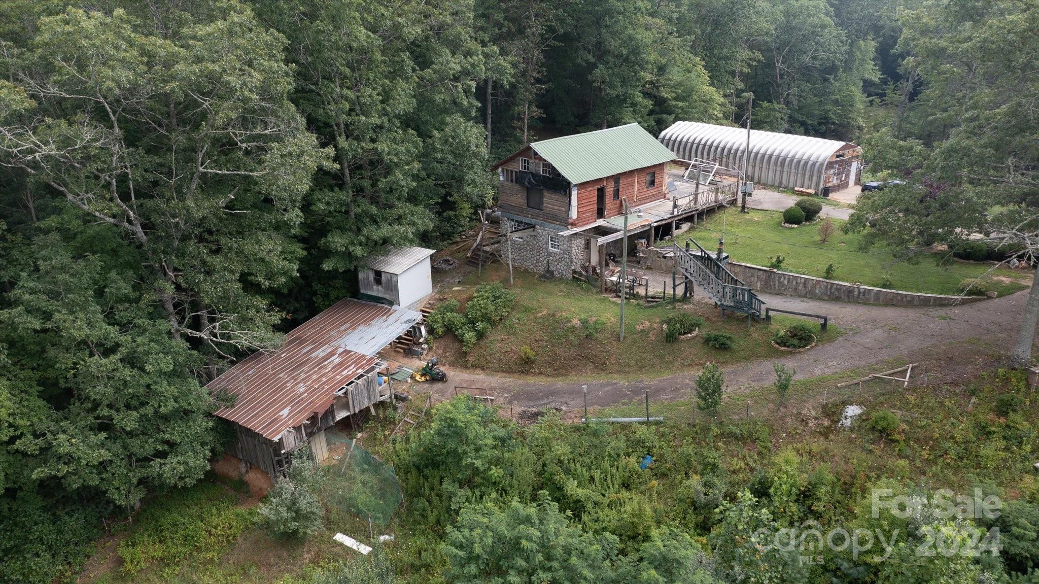 an aerial view of a house with outdoor space and trees all around