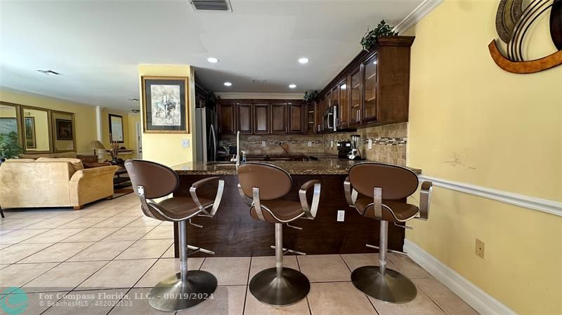 a kitchen with granite countertop a sink a stove a dining table and chairs