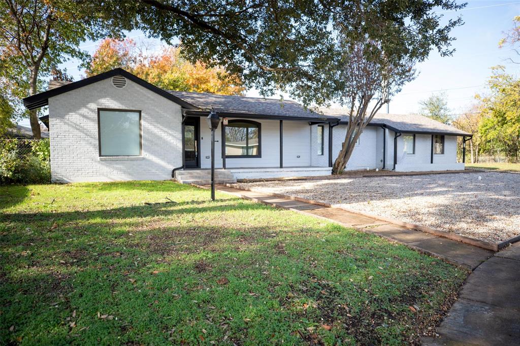 a house that has a big yard next to a large trees