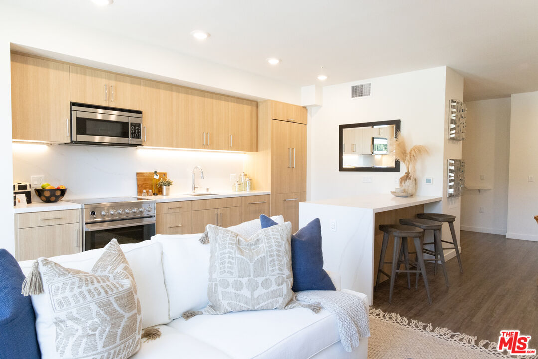 a living room with stainless steel appliances furniture and a kitchen view