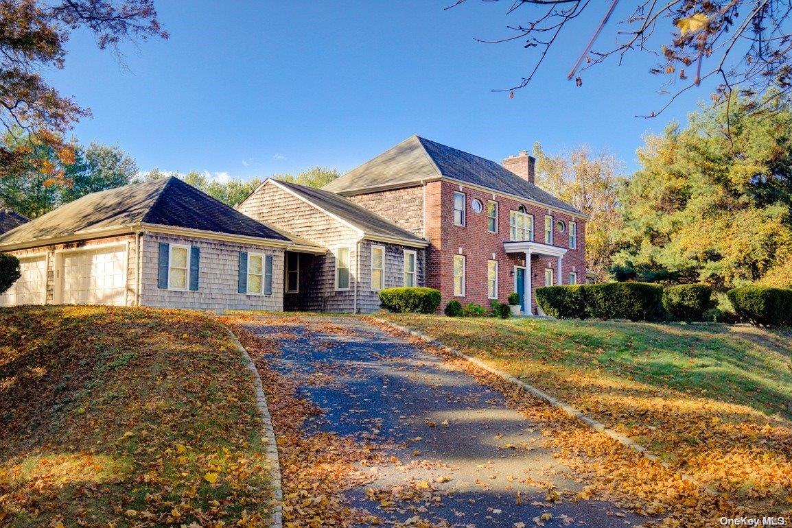 a view of a yard in front of a brick house with a large tree