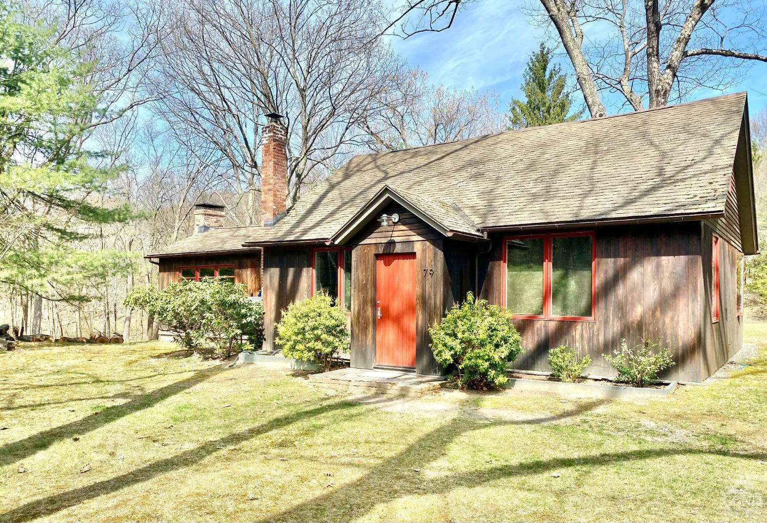 a view of a house with small yard and large tree