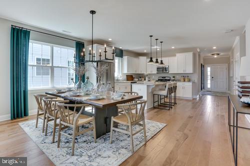 a view of a dining room and livingroom with furniture wooden floor a chandelier