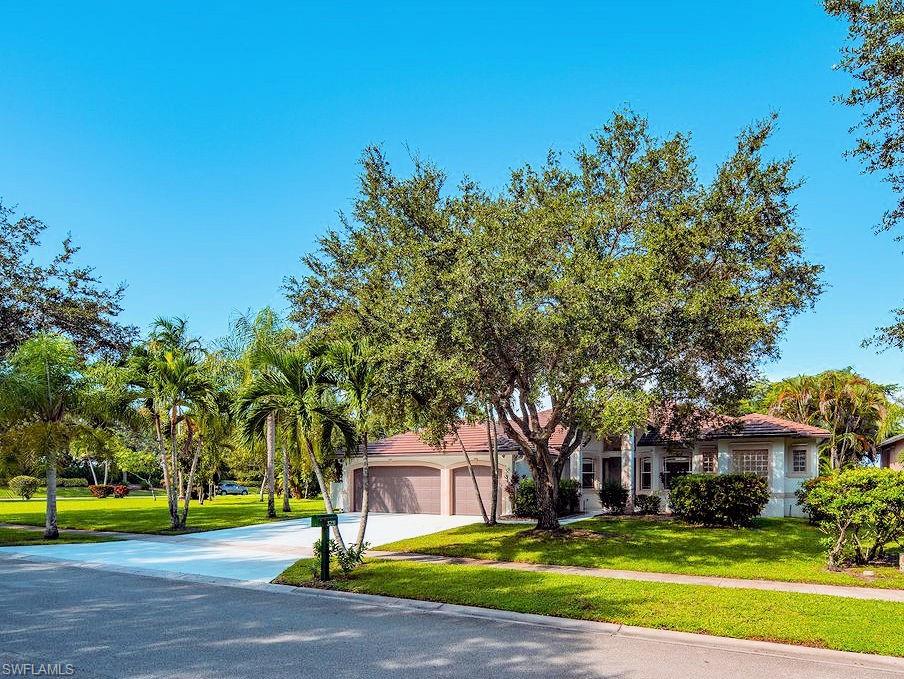 a view of a house with a big yard and large trees