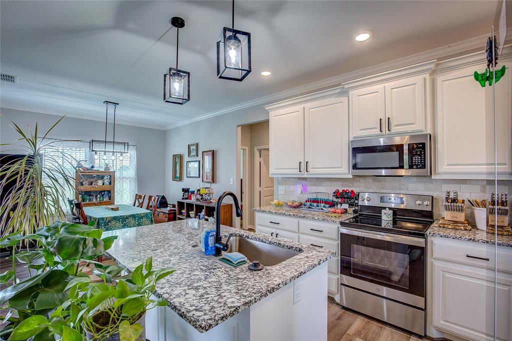 a kitchen with stainless steel appliances granite countertop a sink a stove and a wooden cabinets