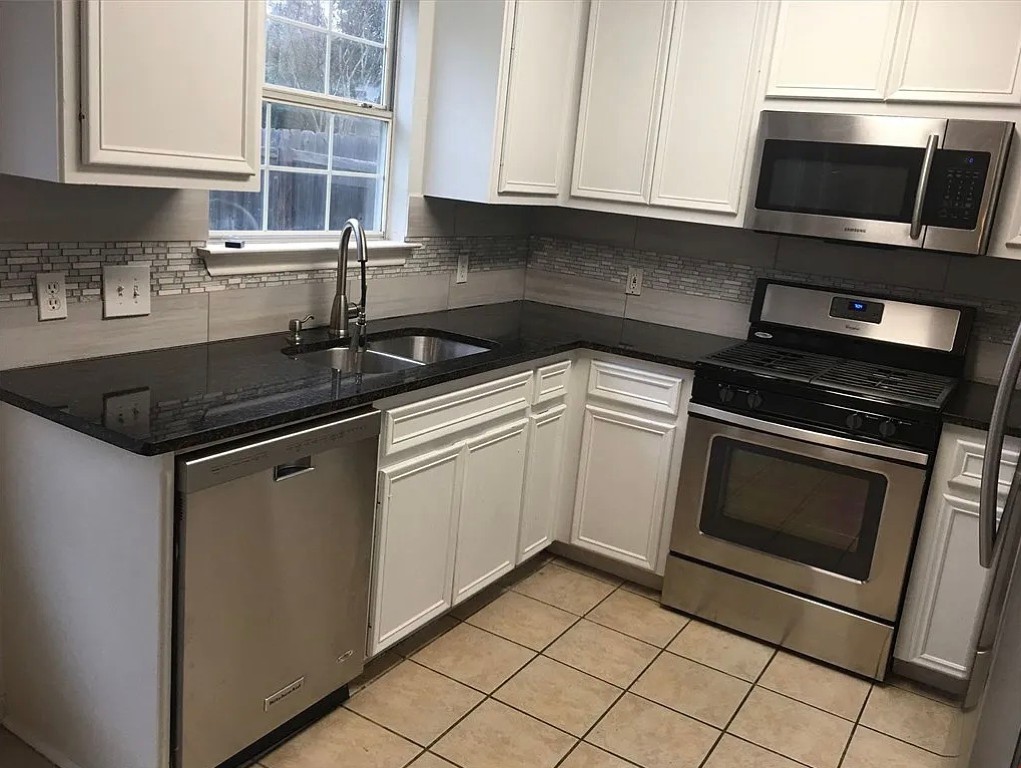 a kitchen with granite countertop white cabinets and stainless steel appliances