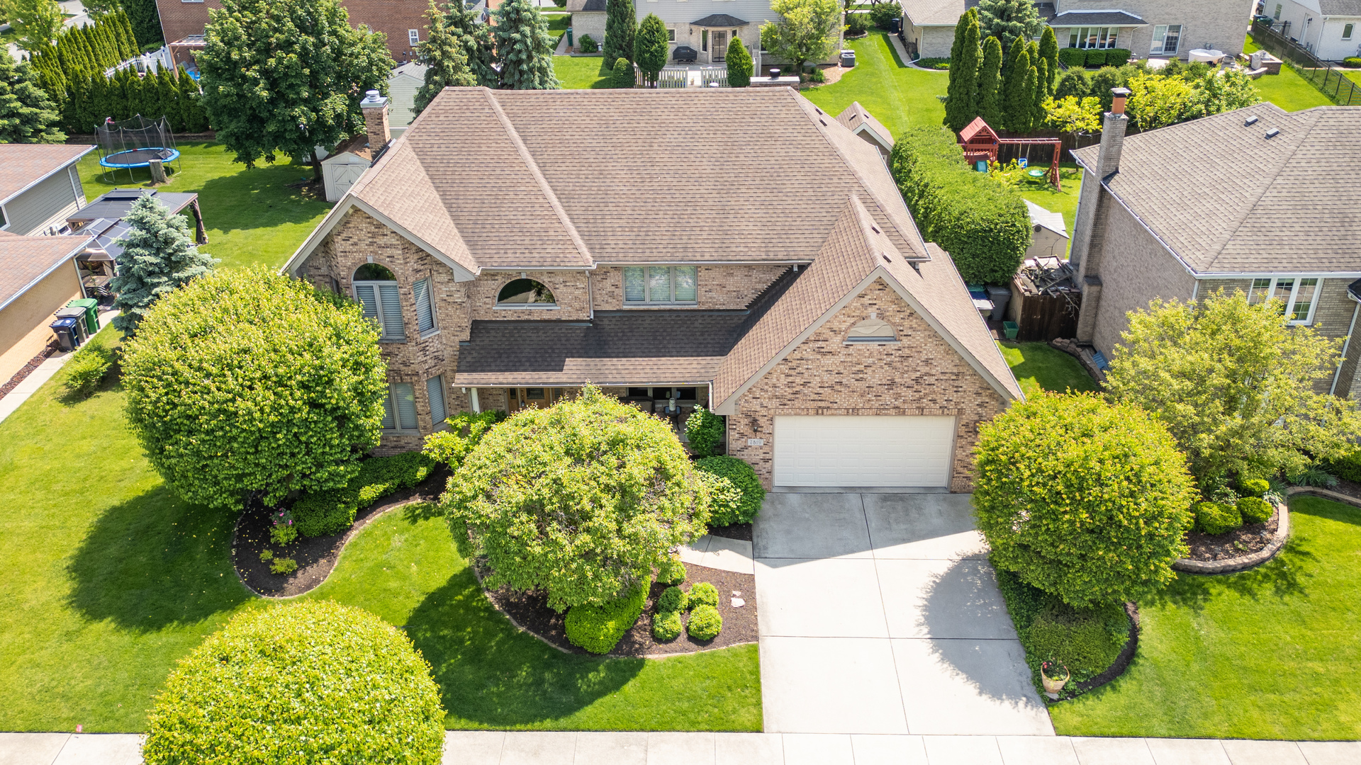 a aerial view of a house with large trees and flower plants