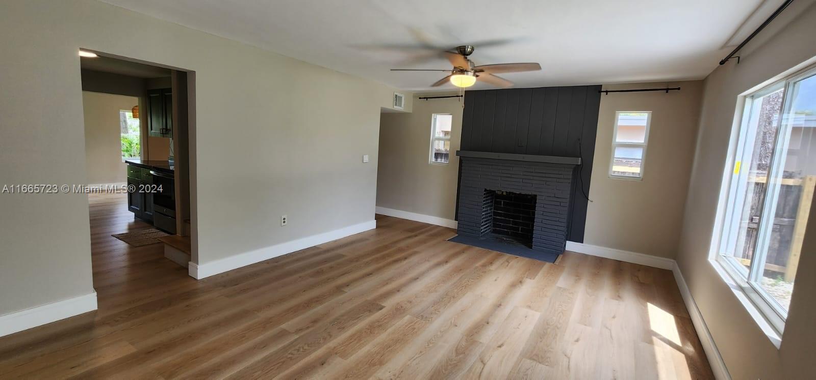 an empty room with wooden floor fireplace and windows