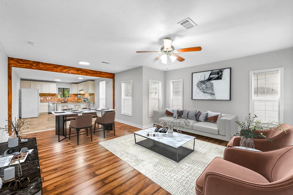 a living room with furniture kitchen view and a wooden floor