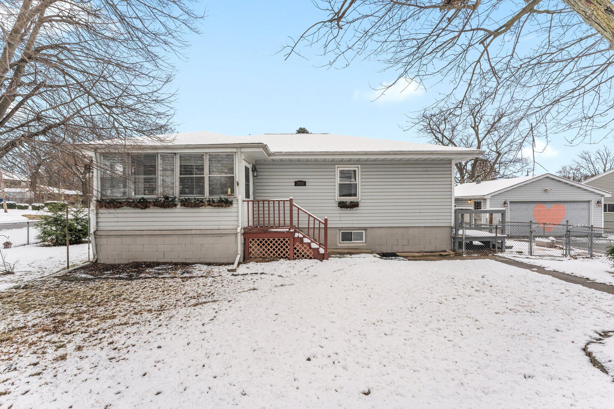 a front view of a house with a yard covered in snow